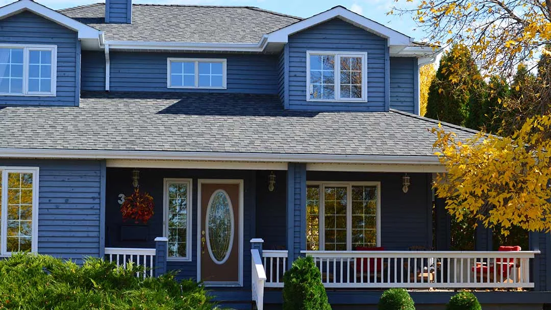 A blue house featuring a porch and front steps, with a Gutter Guard visible along the roofline.